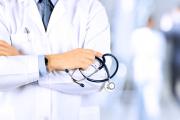 View of male doctor's torso as he stands holding a stethescope.