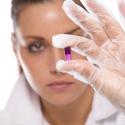 Woman wearing latex glove holds up experimental drug.