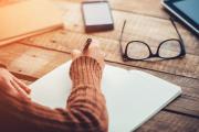 Woman writing memo at desk.